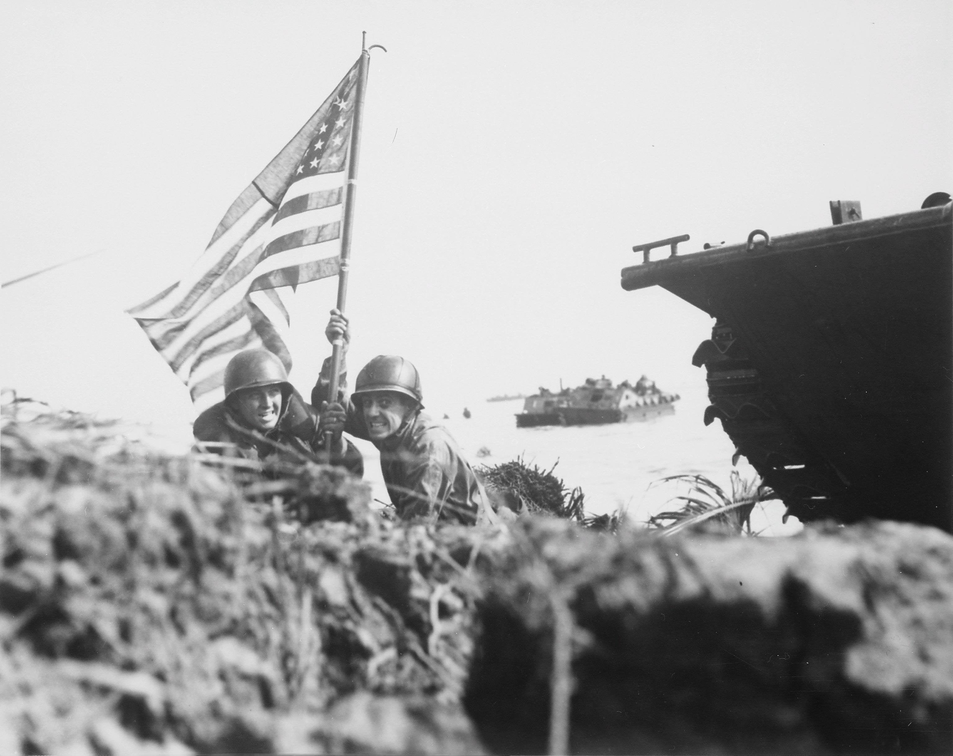 First flag on Guam on boat hook mast. Two U.S. officers plant the American flag on Guam eight minutes after U.S. Marines and Army assault troops landed on the Central Pacific island on July 20, 1944.
